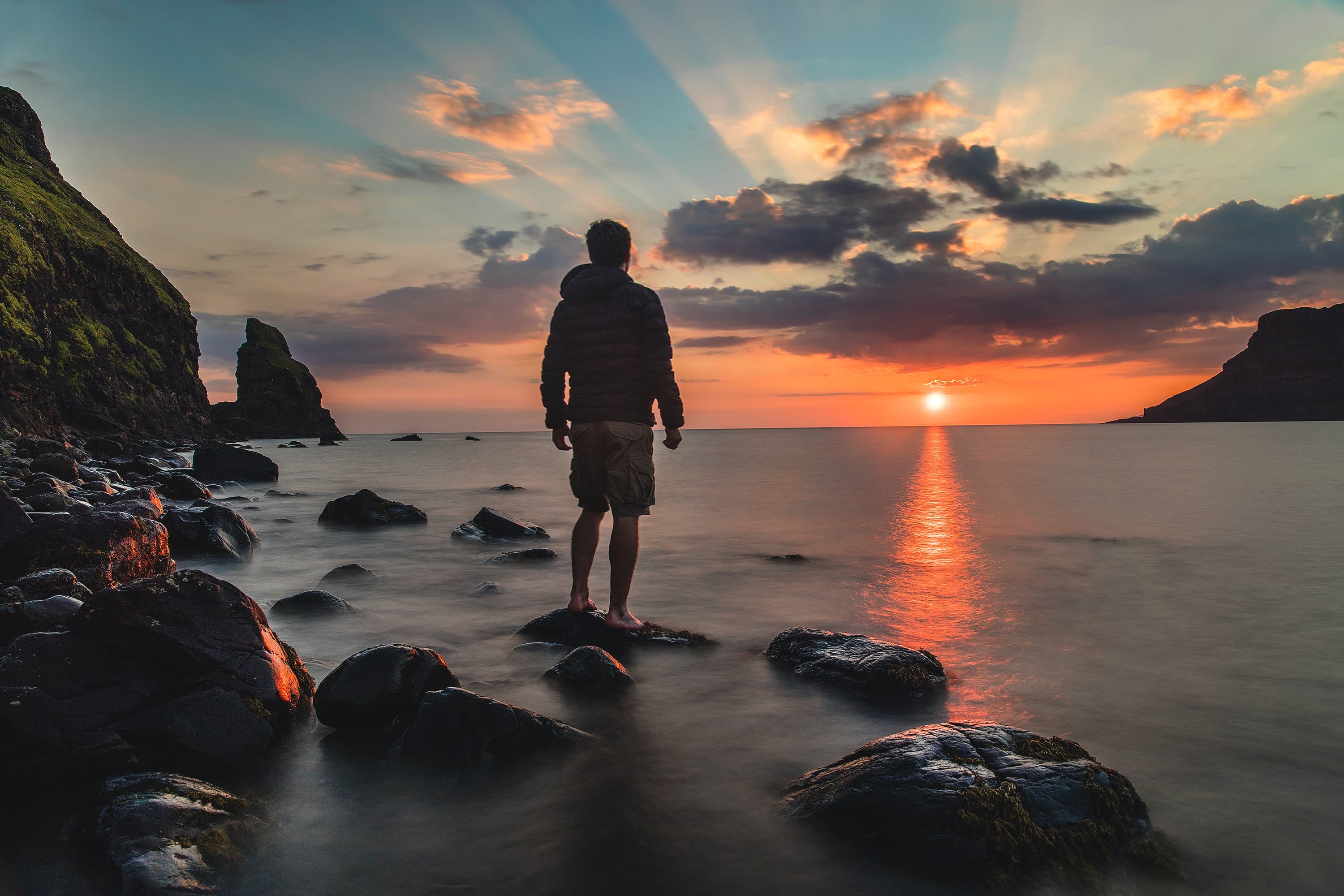 A calm figure looking out over a serene beach at dawn